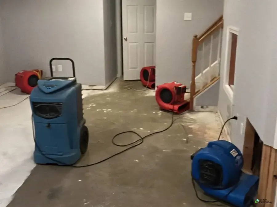 Dehumidifier and air movers drying a hallway beside the stairs in a Smyrna home