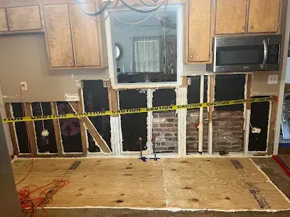 Kitchen wall opened to the studs with caution tape after a leak