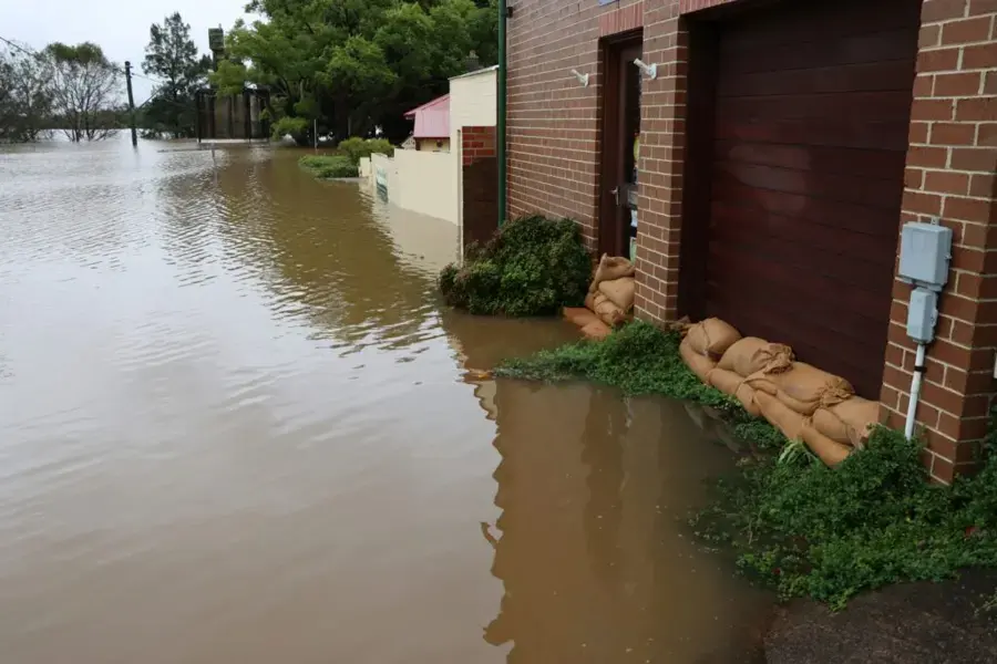 Floodwater rising against sandbags at a garage door after heavy rain