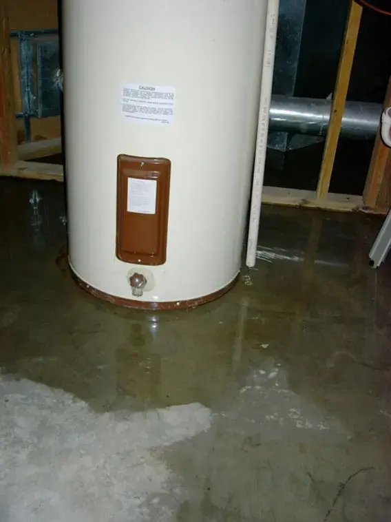 Tank water heater standing in water spread across the floor
